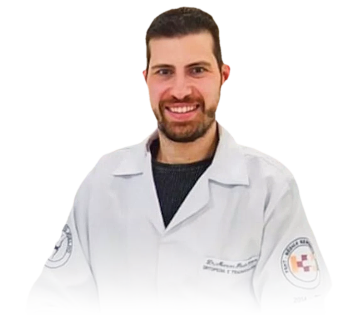 Dr. Marcos Paulo Vanzin sorrindo, de jaleco branco, sentado à mesa do consultório